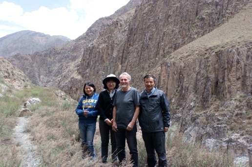 Professor Dorrik Stow with colleagues in the field beside steeply-dipping rock strata in a mountain landscape