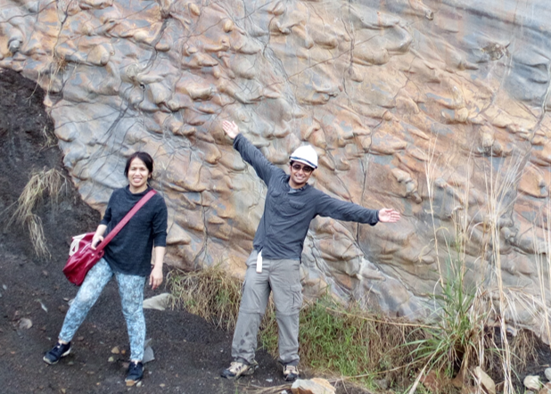 Researchers in front of a striking patterned rock face during a field project