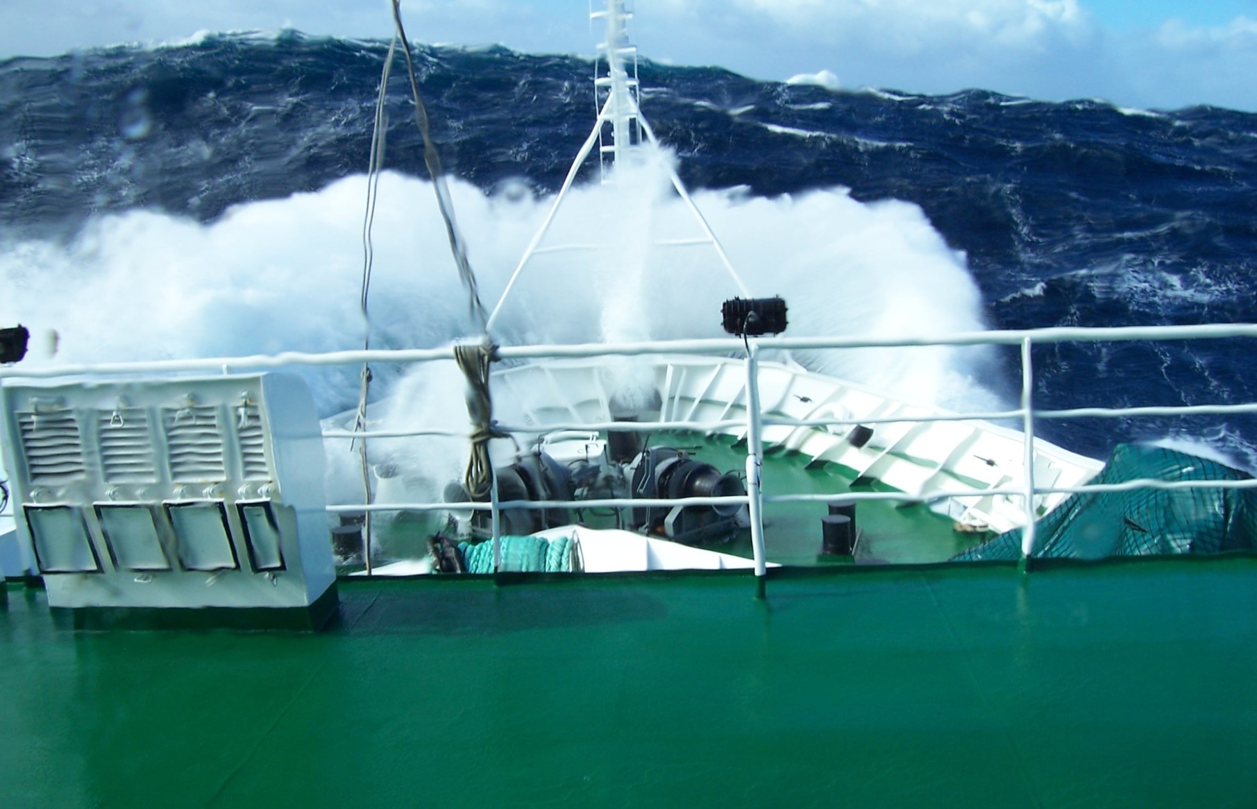 A wave breaks over the bow of a research vessel in heavy seas